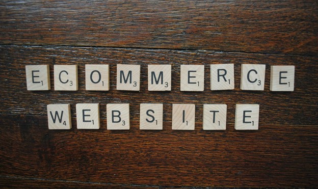 Wooden letter tiles spelling out the words ecommerce website on a dark wood surface